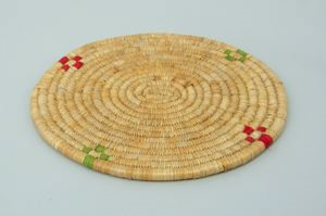 Image of round coiled grass mat with red and green decoration